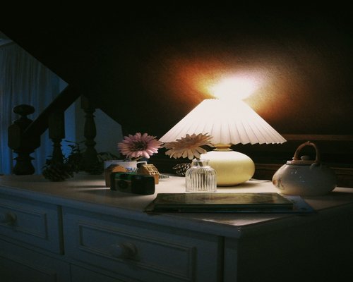A physical book illuminated by a warm desk lamp in a cozy room